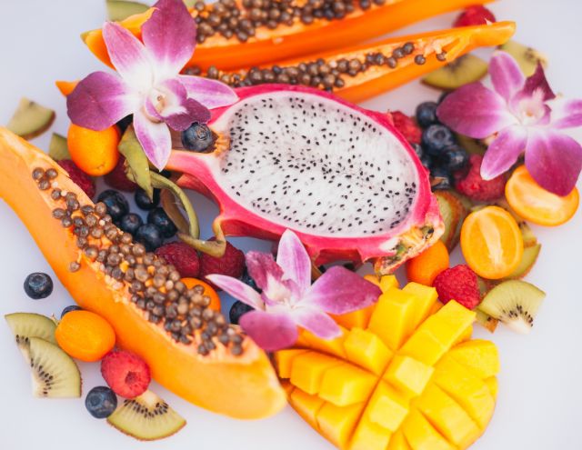 A variety of sliced fruits and orchid flowers on a white background.