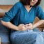 Asian woman with hands on her stomach feeling IBS pain