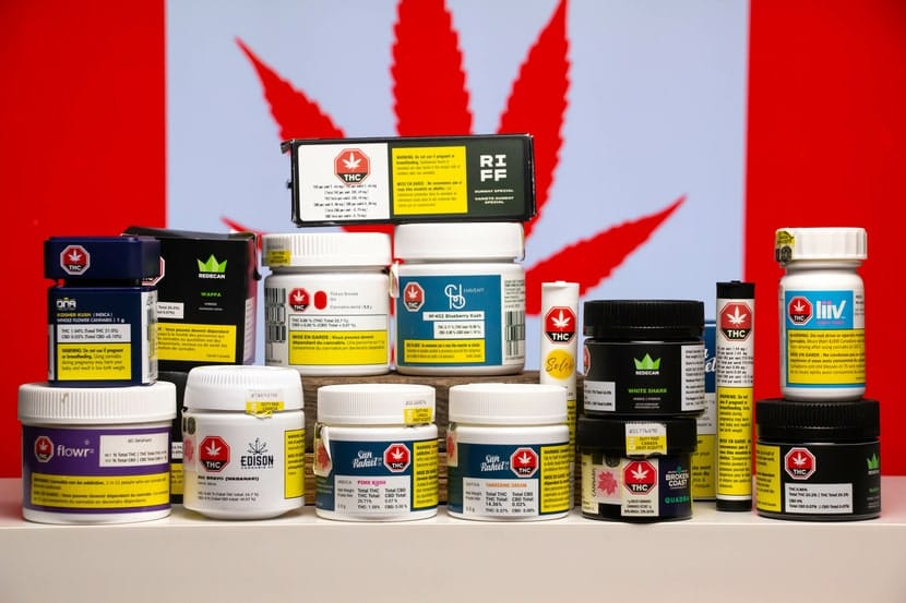 Display of Canadian cannabis product containers in front of a red maple leaf, showcasing legal cannabis branding in Canada.
