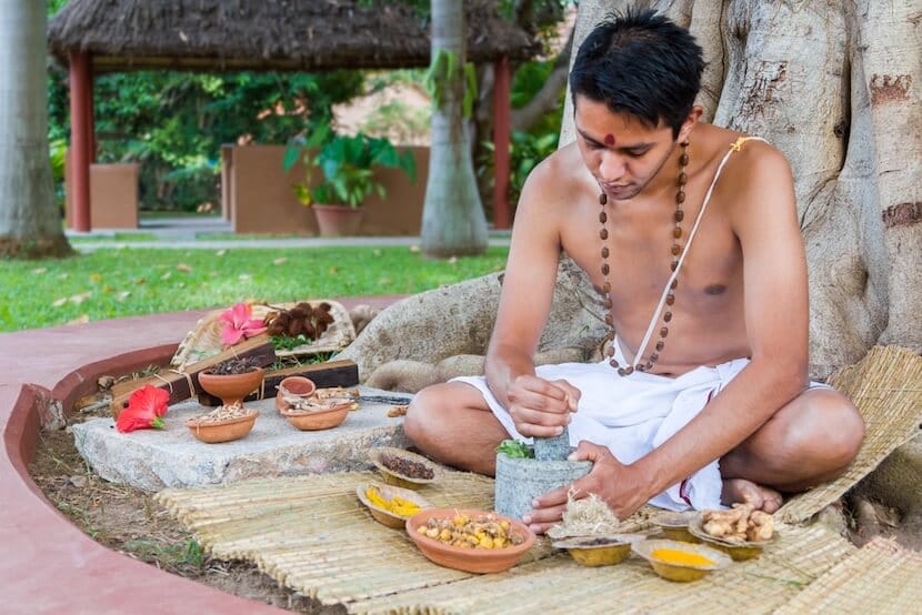 A young man preparing Ayurvedic medicine in the traditional manner.