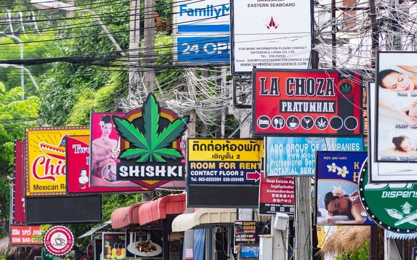 Colorful street signs in Pattaya, Thailand, including several cannabis-themed logos.