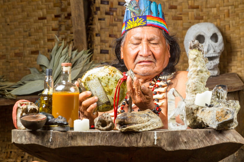 A shaman in Ecuador performs a traditional healing ritual with ayahuasca, surrounded by totems and participating in a sacred ceremony.